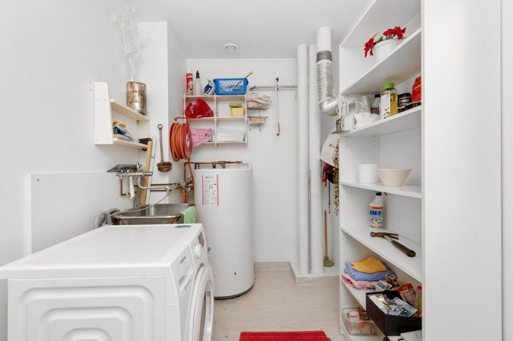 a-laundry-room-19980200 Clean and organized home laundry room with washing machine, shelves, and water heater.