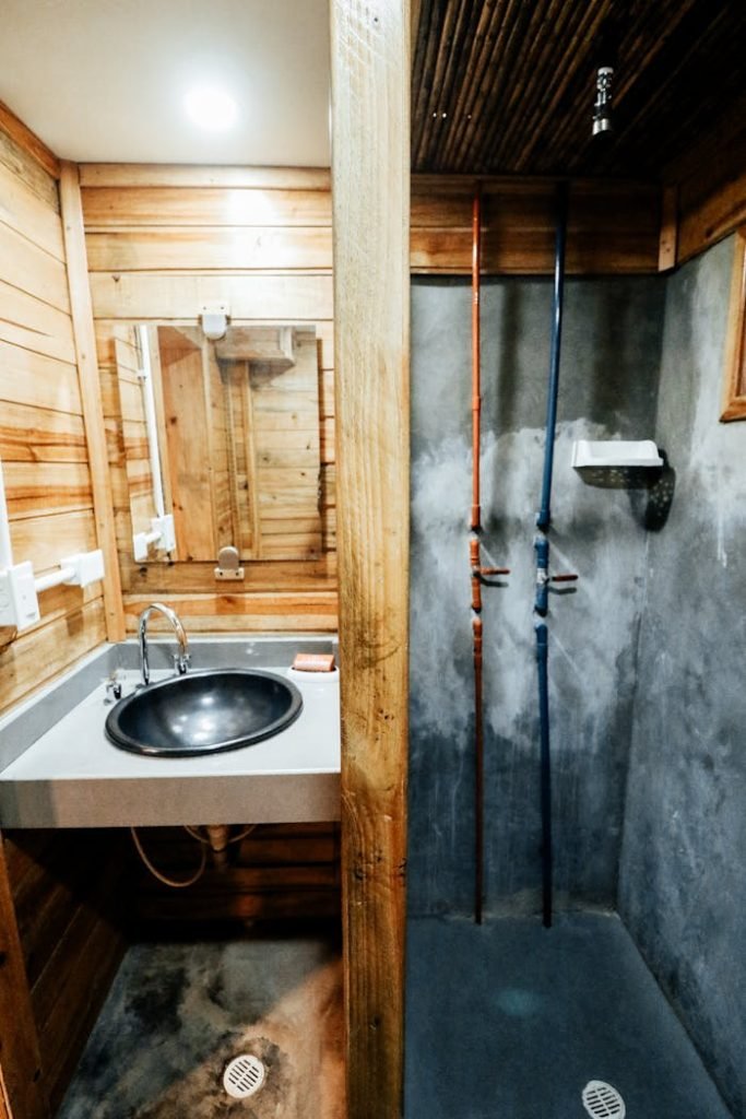 sink-and-shower-in-bathroom-11062798 A rustic bathroom with wood paneling and concrete shower offering a cozy and natural design.